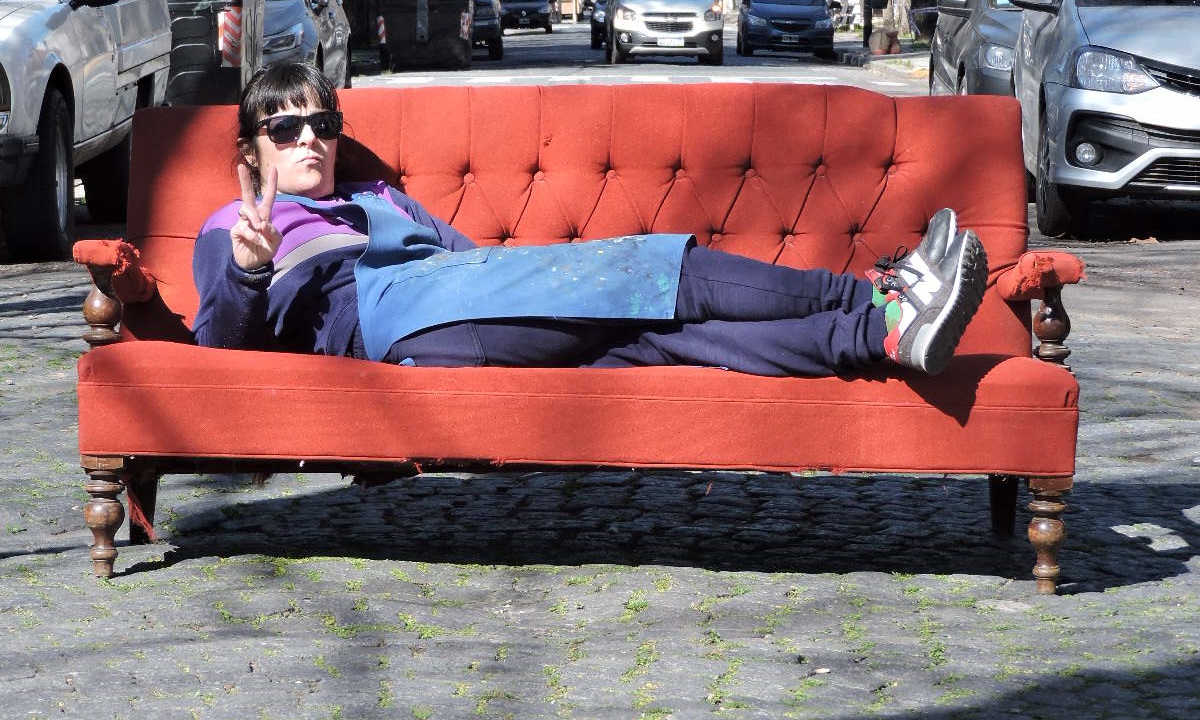 Anita recostada en un sofá rojo en la calle